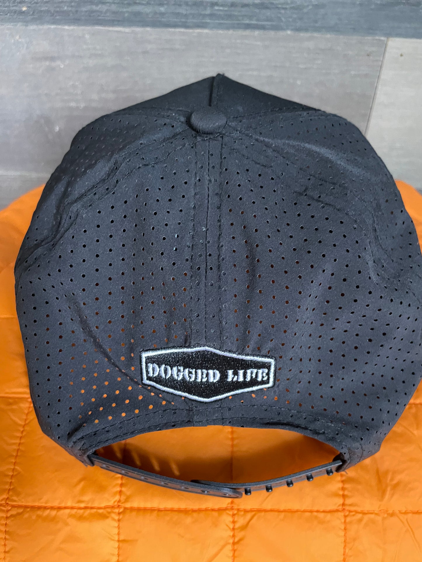 Black perforated Tritech cap with Dogged Life patch and adjustable snap closure, perfect for outdoor wear.