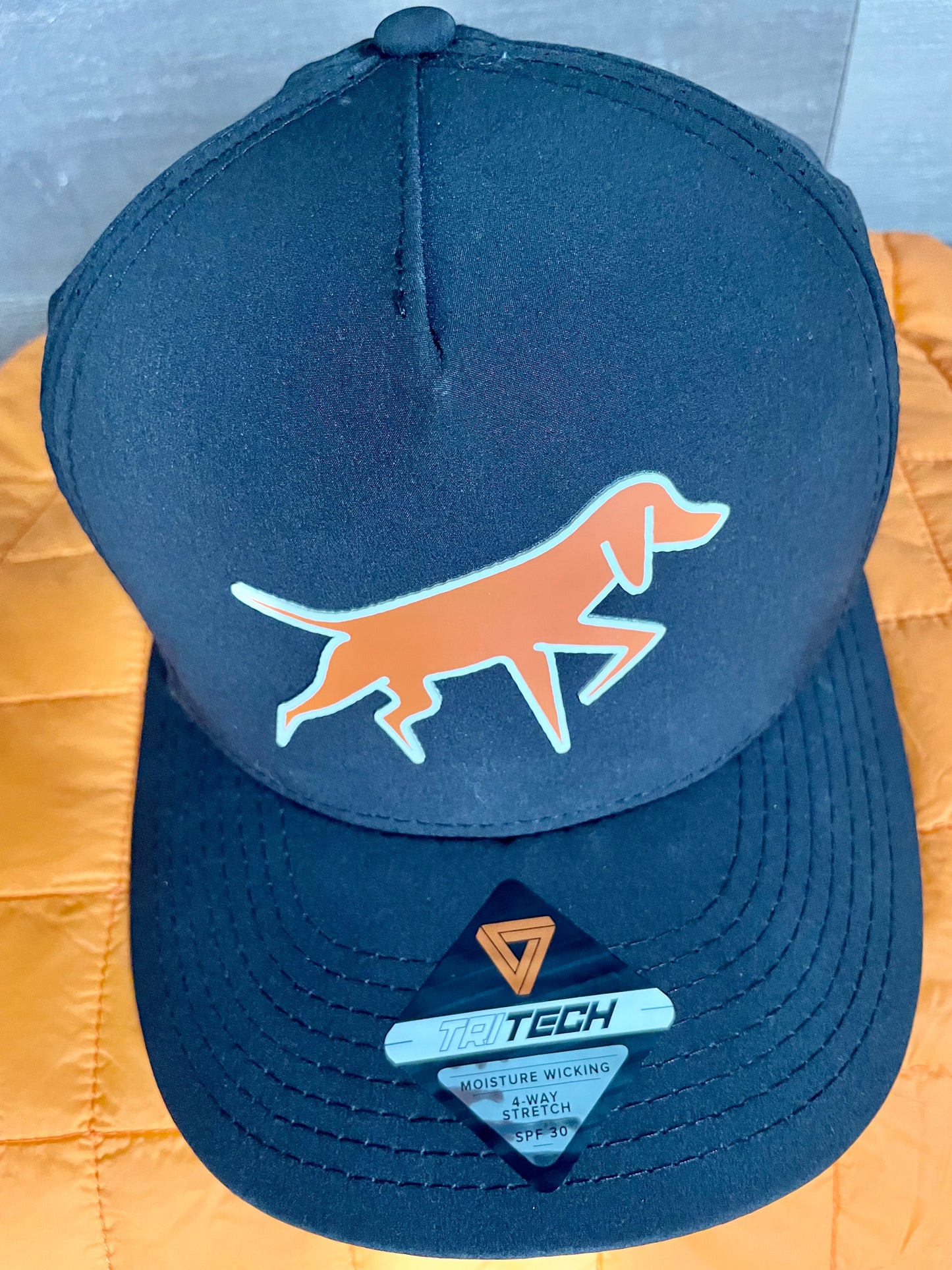 Dogged Life black perforated Tritech cap with orange Bongo patch, moisture-wicking, SPF 30, and 4-way stretch.